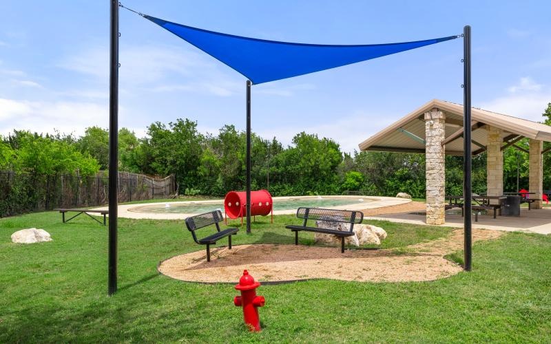 shaded benches in bark park with play equipment for pets