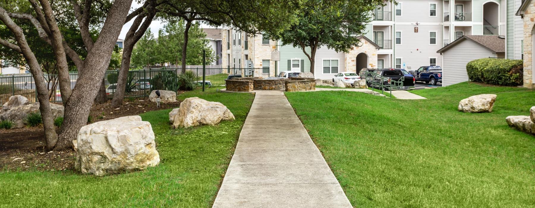 walkway leading to outdoor fire pit surrounded by beautiful landscaping